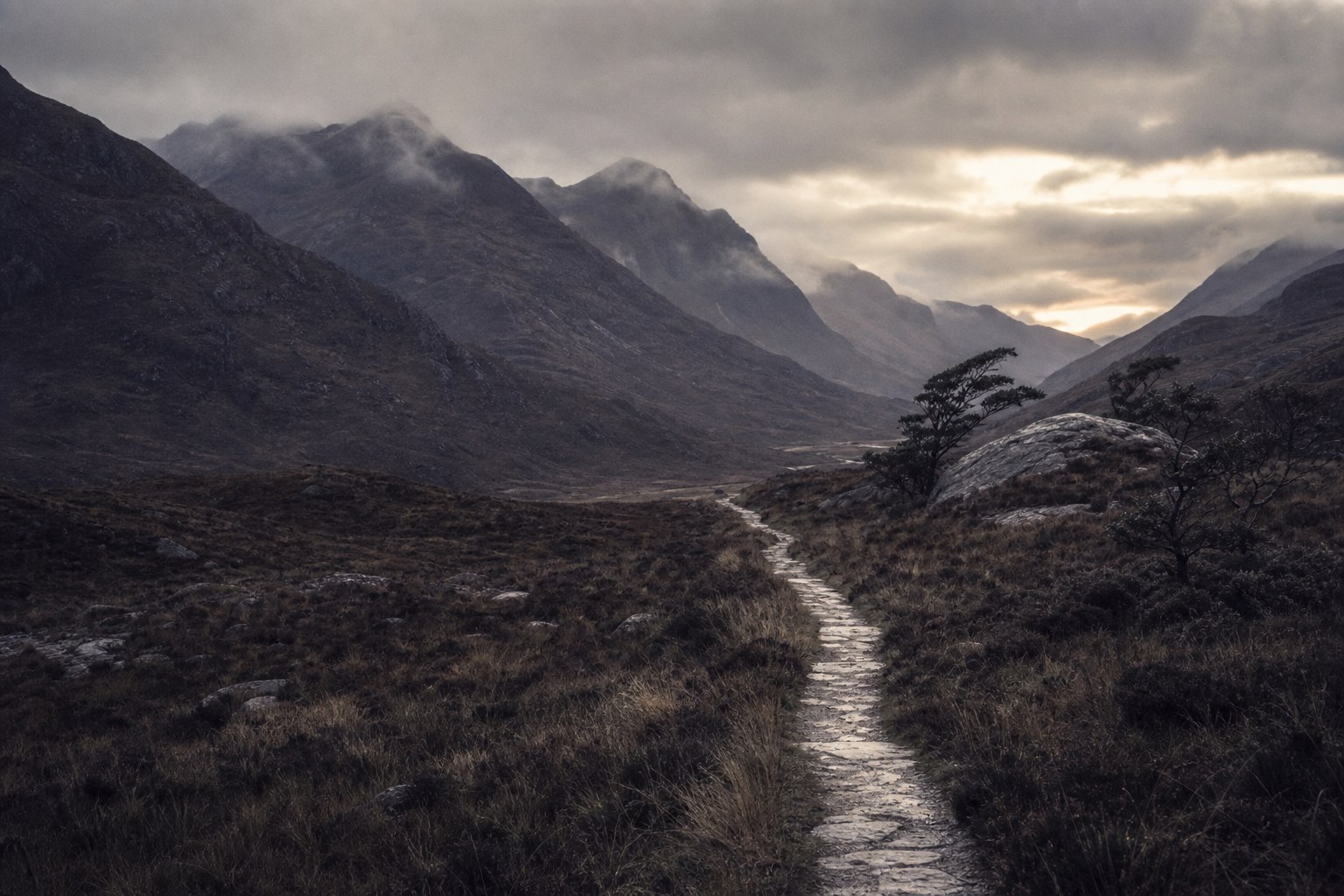 A trail leading through a misty mountain valley